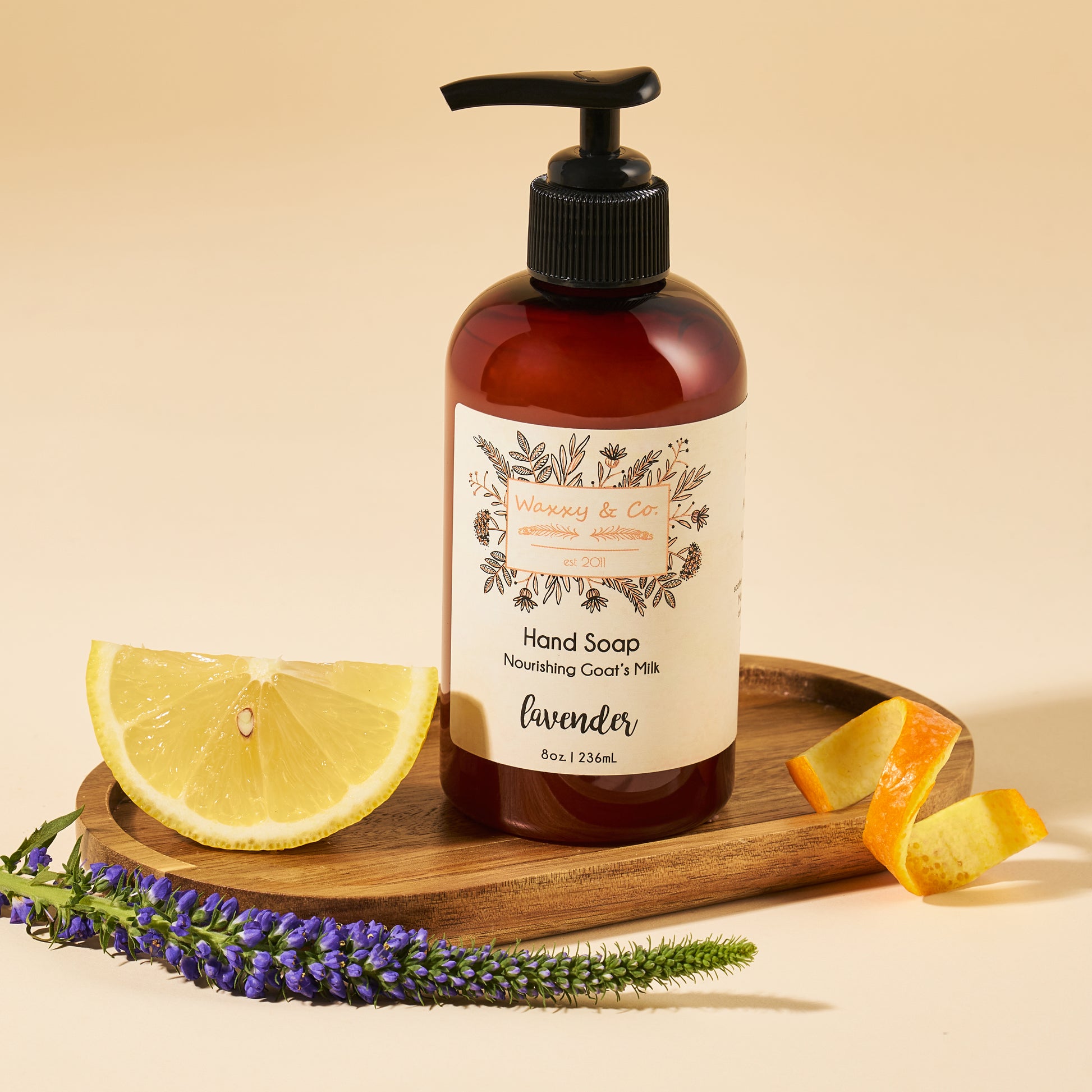 Hand soap bottle with a label on a wooden tray with lemon, orange, and lavender.